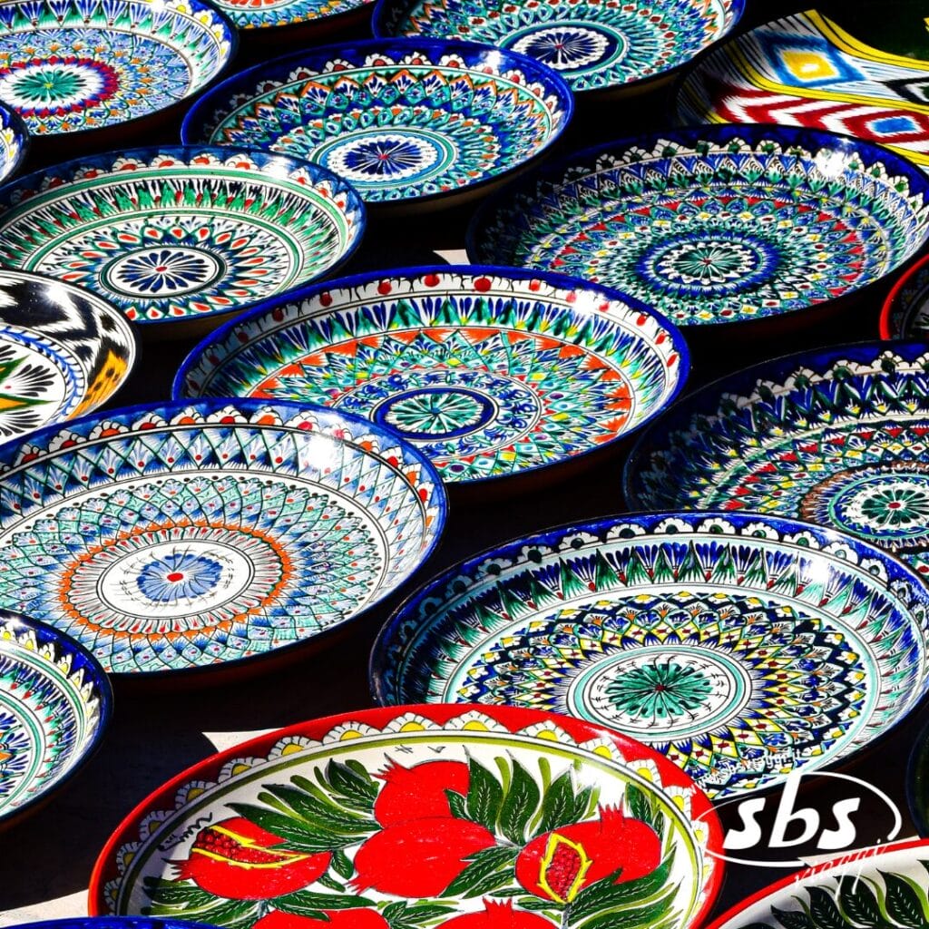 Una collezione di piatti in ceramica Terra di Tamerlano colorati e dai motivi intricati, disposti uno vicino all'altro su una superficie piana.