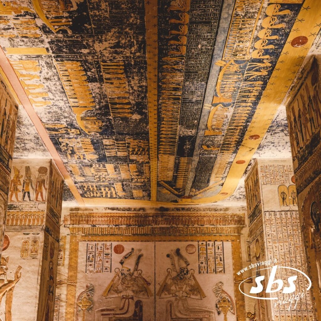 Interno di una tomba dell'antico Egitto con intricati geroglifici e colorati dipinti su pareti e soffitto, con evidenti segni di usura e scolorimento: una tappa obbligata durante una Crociera sul Nilo o un qualsiasi Tour Egitto immersivo.