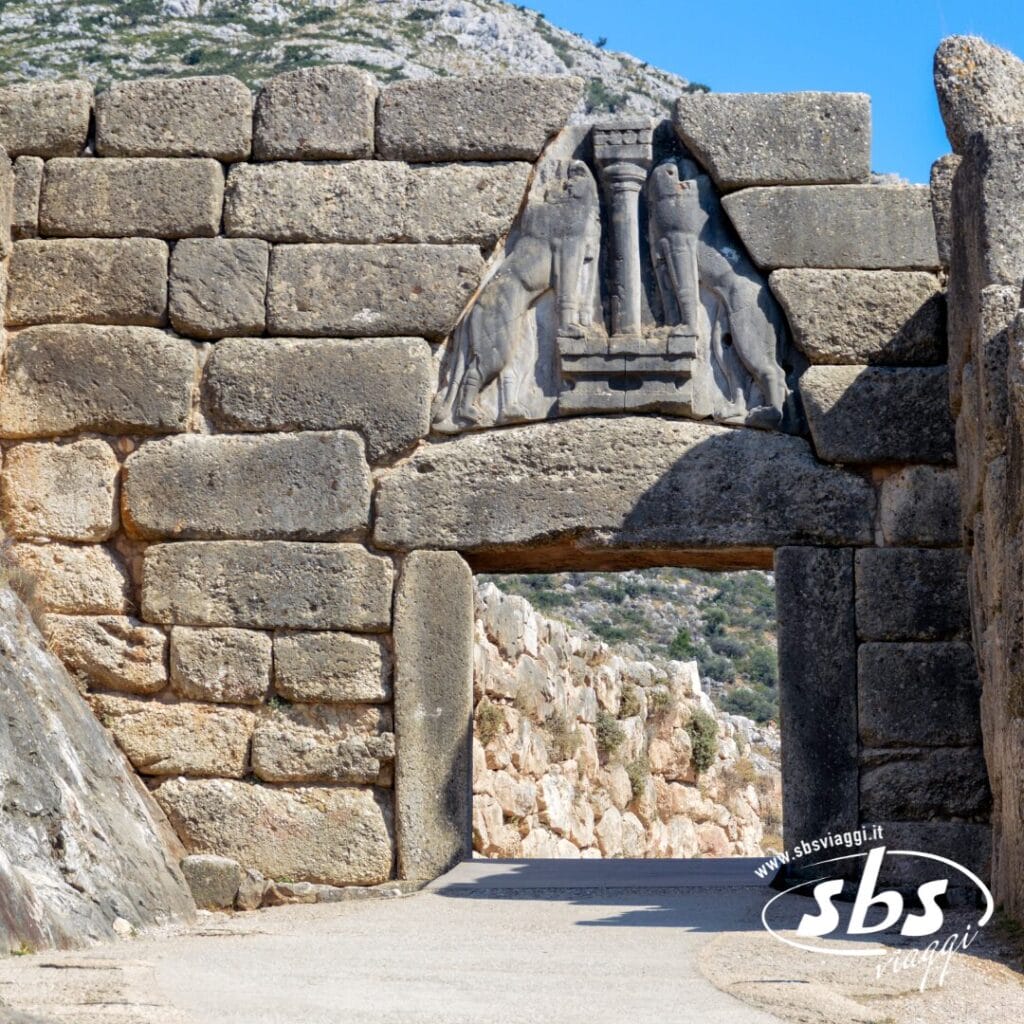 Porta in pietra con un leone scolpito in rilievo sopra l'ingresso, circondata da grandi blocchi di pietra e colline sullo sfondo: un esempio sorprendente della Grecia Classica, perfetto per la tua prossima avventura nel Tour Grecia.