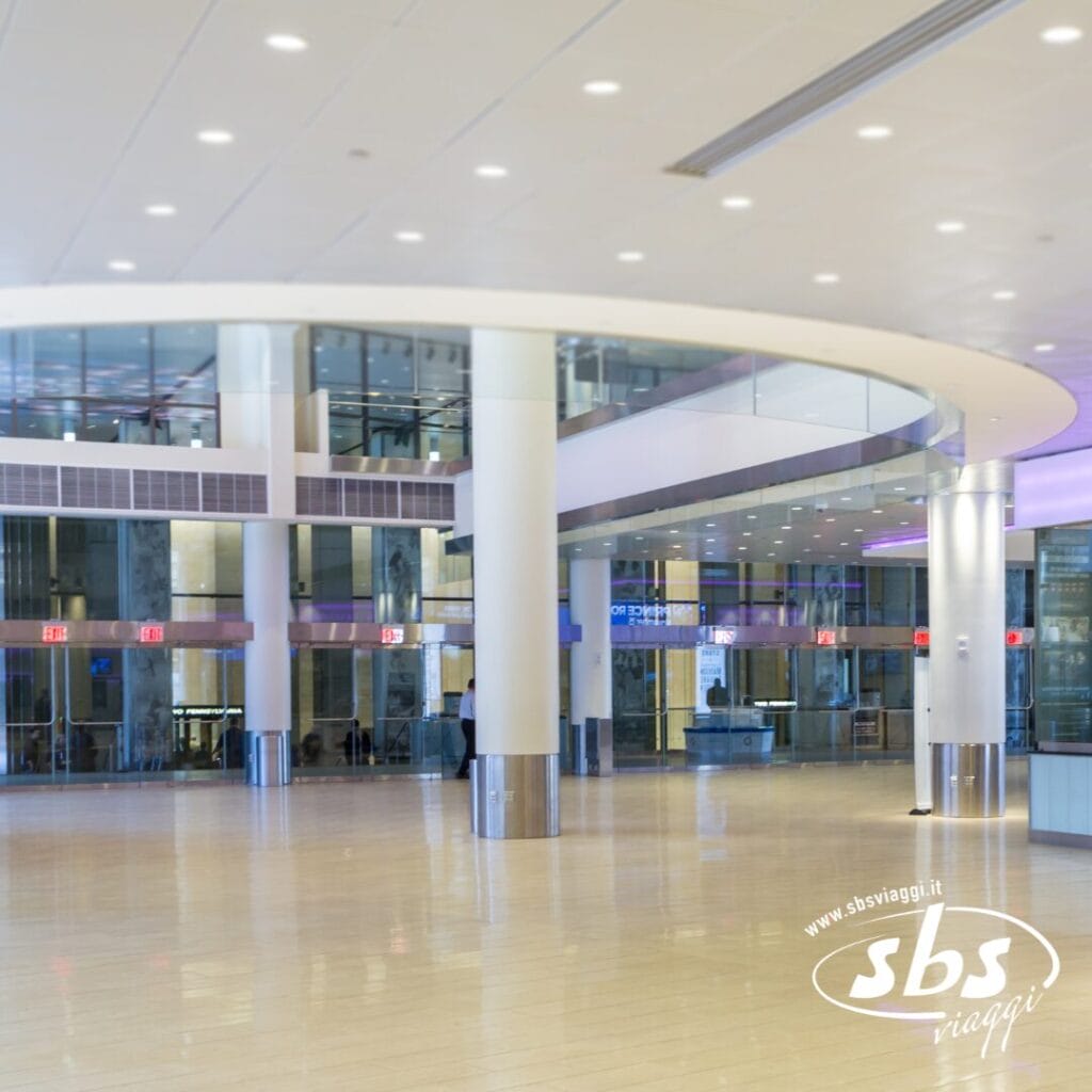 Interni spaziosi e moderni del terminal aeroportuale, con ampie vetrate, colonne bianche e pavimenti lucidi, che richiamano la vibrante energia dell'NBA Experience al Madison Square Garden. Il logo