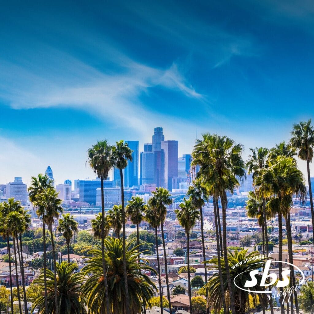 Lo skyline del centro di Los Angeles con alte palme in primo piano sotto un cielo azzurro, cattura lo spirito cittadino dell'Essential 1924.