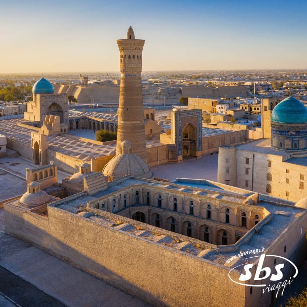 Vista aerea di antichi edifici e di un alto minareto nella città storica di Bukhara, Uzbekistan (Terra di Tamerlano), con cupole e architettura color sabbia sotto un cielo limpido.