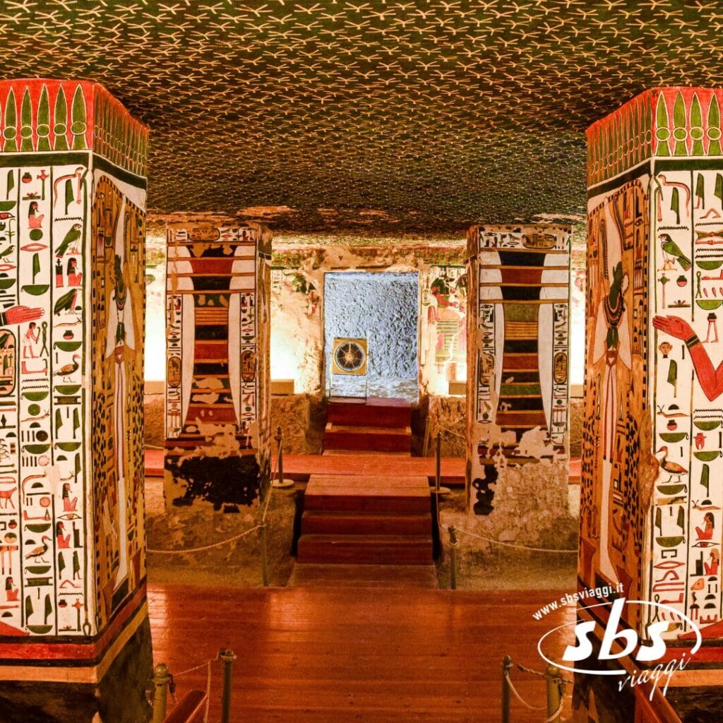 Interno di un'antica tomba egizia con colonne dipinte a colori vivaci, geroglifici e pareti decorate con opere d'arte dettagliate: uno sguardo alla storia perfetto per la tua avventura nel Tour Egitto o nella Crociera sul Nilo.