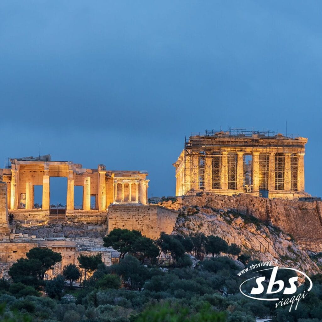 Le rovine illuminate dell'Acropoli, tra cui il Partenone, sono visibili al tramonto ad Atene, in Grecia: uno spettacolo iconico di qualsiasi tour Grecia o viaggio Grecia, con impalcature visibili su una parte della struttura.