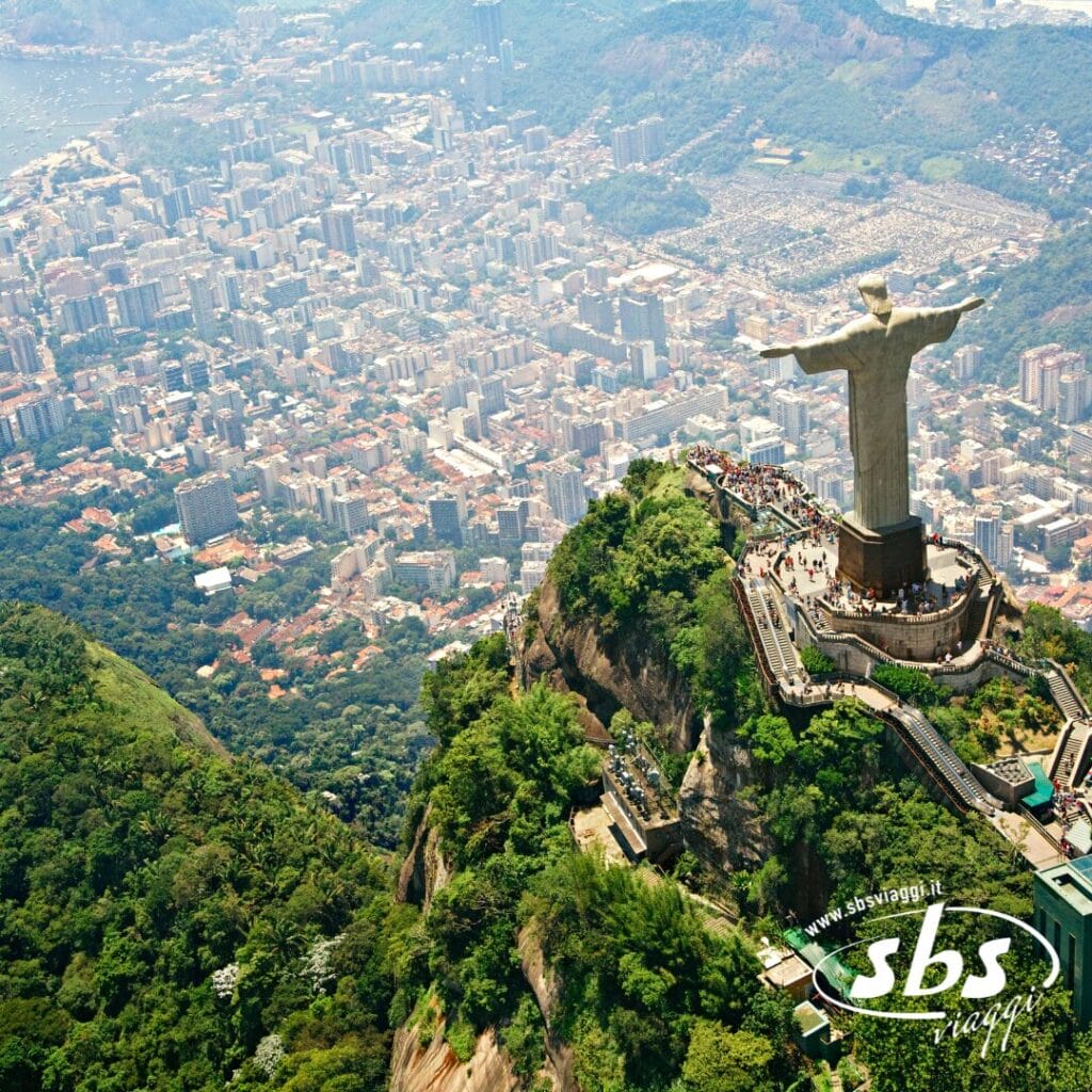 Vista aerea della statua del Cristo Redentore in cima a una montagna verde che domina il paesaggio urbano di Rio de Janeiro, in Brasile, nel vivace Sud America.
