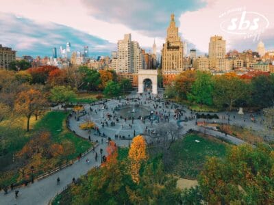 Vista aerea di Washington Square Park a New York, con persone che passeggiano, alberi autunnali ed edifici cittadini sullo sfondo.