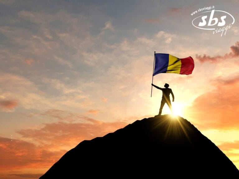 Al tramonto, una persona è in piedi sulla cima di una montagna vicino al confine tra Romania e Bulgaria, tenendo con orgoglio una bandiera rumena: il finale perfetto per un tour indimenticabile.