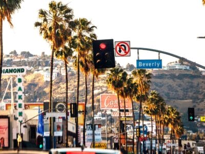 Una soleggiata scena di strada a Los Angeles con palme, semafori e segnali stradali per Diamond e Beverly, sullo sfondo di colline ed edifici: cattura perfettamente lo spirito di un'avventura cittadina dell'Explorer 1924.
