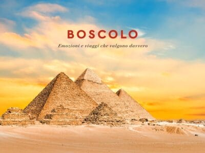 Tre piramidi nel deserto al tramonto, evocanti l'Antico Egitto, con il testo "Boscolo Emozioni e viaggi che valgono davvero.