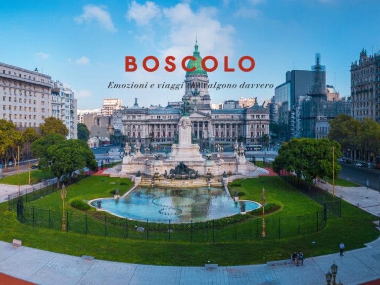 Una grande piazza con una fontana e una statua, circondata da edifici storici sotto il cielo azzurro di Buenos Aires. Il testo recita: "BOSCOLO".