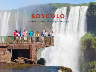 Turisti su una piattaforma ad una grande cascata in Sudamerica; il testo recita "BOSCOLO Emozioni e viaggi che valgono davvero.