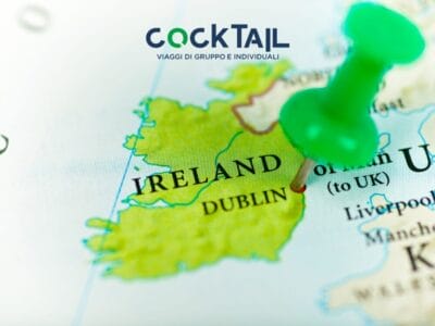 Una puntina verde segna Dublino, Irlanda, su una mappa con sopra il testo di viaggio "COCKTAIL" e un accenno alla ricetta di un cocktail irlandese.