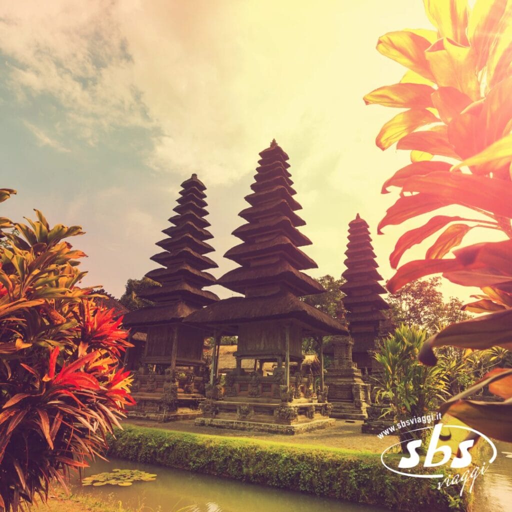 Strutture templari tradizionali balinesi con tetti a più livelli circondate da una vegetazione lussureggiante, fotografate sotto la calda luce del sole: scopri la bellezza e i segreti di Bali che ti aspettano nel tuo prossimo tour a Bali.