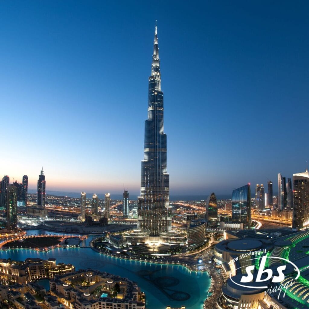 Il Burj Khalifa a Dubai al tramonto, con le luci della città che brillano; logo