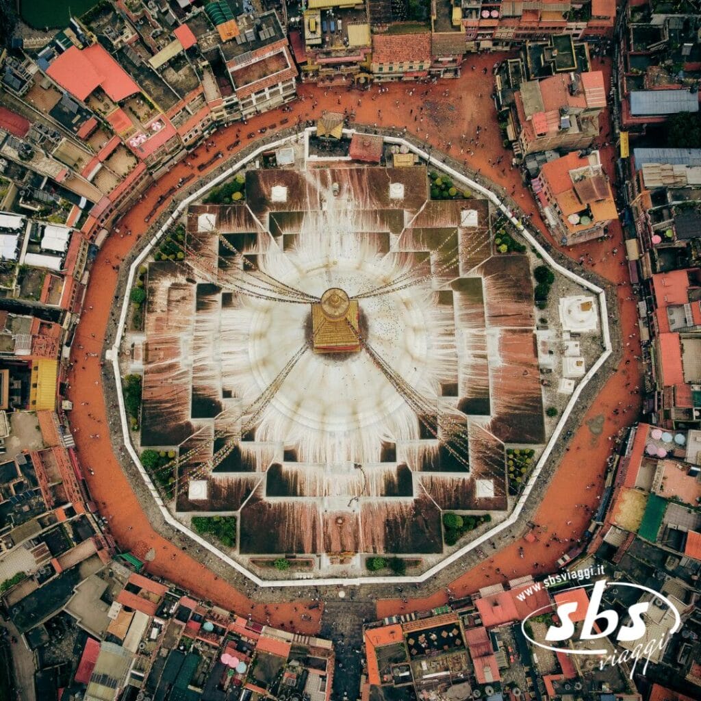 La vista aerea dello Stupa di Boudhanath a Kathmandu, in Nepal, mostra la sua cupola bianca, la guglia dorata e la piazza circolare, un'attrazione iconica di qualsiasi tour in Nepal, in mezzo a edifici densamente popolati.