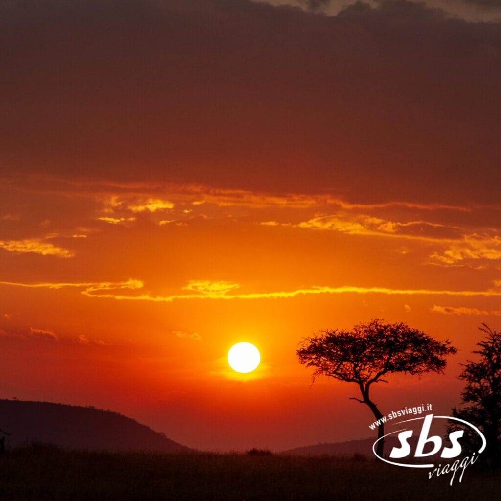Tramonto sulla savana della Tanzania, con alberi e colline in controluce sotto un cielo arancione e rosso, che cattura la serena bellezza di Mare.