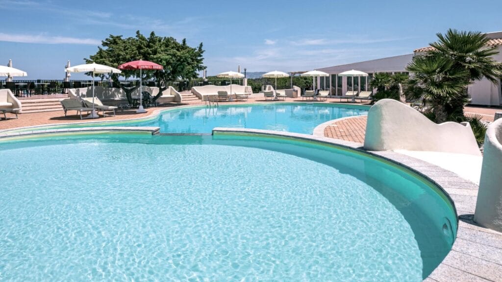 Piscina all'aperto con sedie a sdraio, ombrelloni e cielo azzurro terso in una giornata di sole: la cornice perfetta per una rilassante esperienza Bozza automatica.