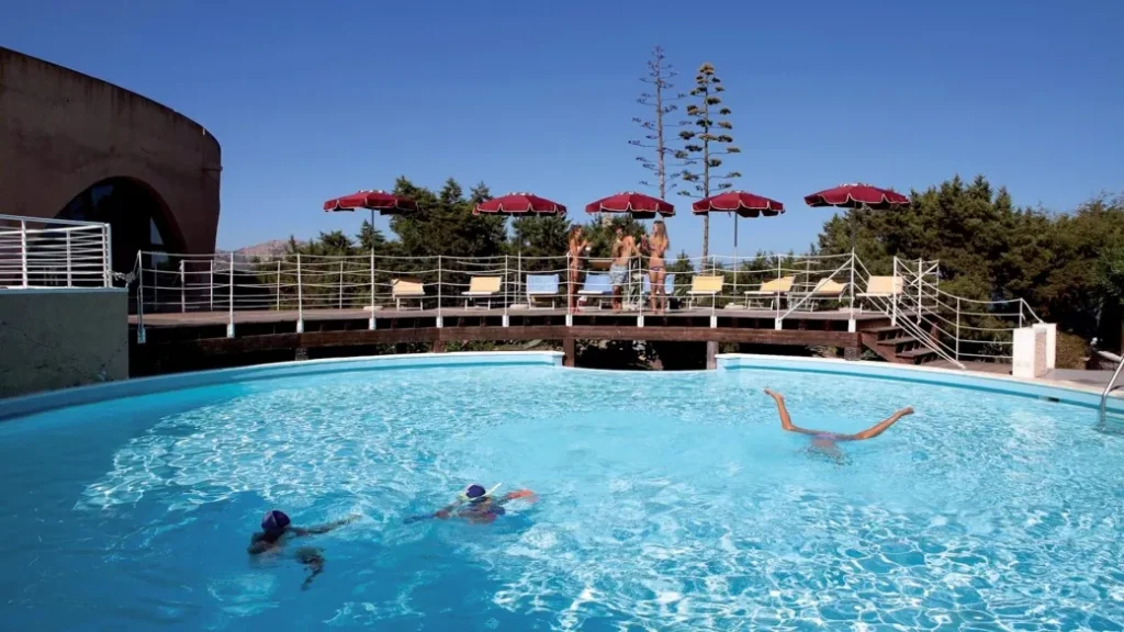 Gli ospiti possono godersi una nuotata nella piscina rotonda all'aperto del Club Esse Roccaruja, dotata di un grazioso ponte, lettini prendisole e ombrelloni rossi, il tutto sullo sfondo dello splendido scenario di Stintino.