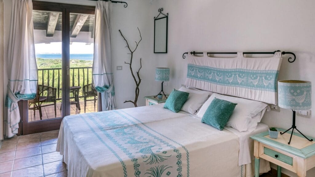 Luminosa camera da letto con decorazioni color verde acqua, letto matrimoniale, porte-finestre e vista sul verde esterno: perfetta per rilassarsi o lavorare alla vostra prossima Bozza automatica.