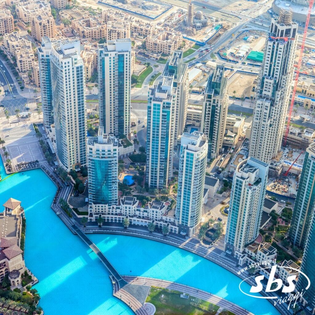 Vista aerea dei moderni grattacieli, del Demo Hotel e di una splendida fontana di acqua blu in un vivace paesaggio urbano.
