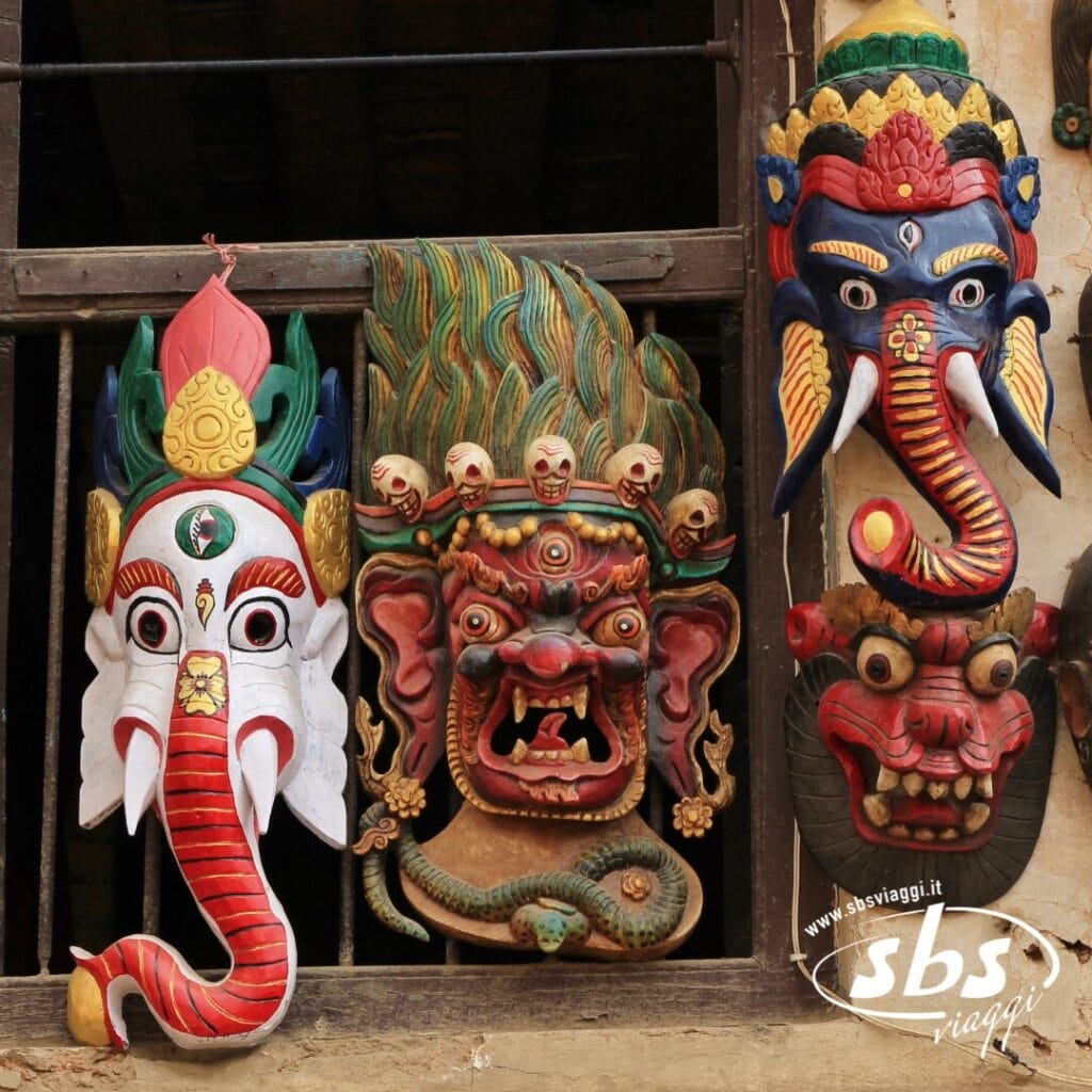 Colorate maschere tradizionali, tra cui due volti di elefante e una divinità feroce, sono esposte su una parete, catturando lo spirito del Festival di Dashain in Nepal nella Valle degli Dei.