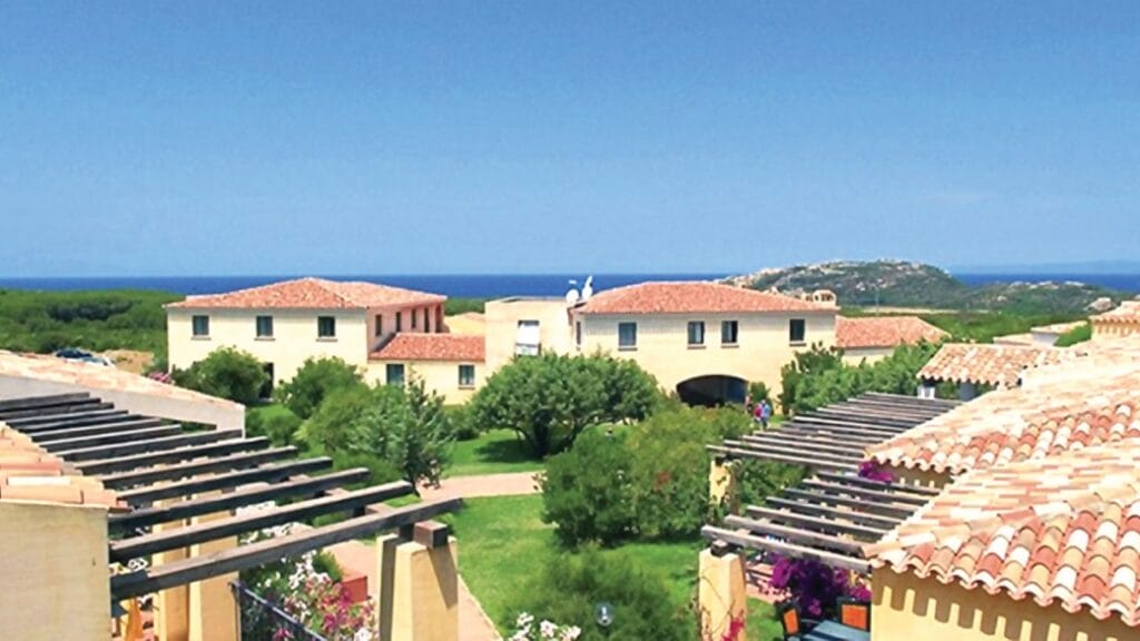Ville in stile mediterraneo con tetti in terracotta, giardini lussureggianti e vista sul mare sotto un cielo azzurro e terso creano uno scenario che ricorda un capolavoro di Bozza automatica.