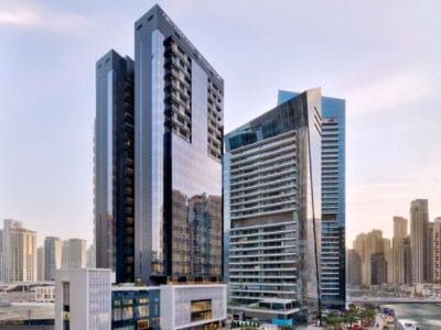 Alti grattacieli moderni con facciate in vetro nello skyline di una città al tramonto, con altri edifici sullo sfondo.