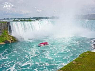 Un'imbarcazione del Tour Splendore dell'Est con passeggeri vestiti di rosso si avvicina alla base delle Horseshoe Falls a Niagara, circondata da nebbia e acqua turchese: uno dei momenti più emozionanti di qualsiasi avventura in Canada.