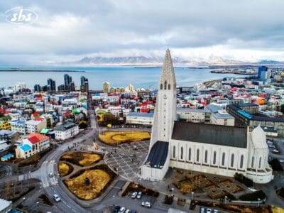Vista aerea della chiesa di Hallgrímskirkja e degli edifici colorati di Reykjavik, che cattura la vera essenza dell'Islanda con le maestose montagne sullo sfondo.