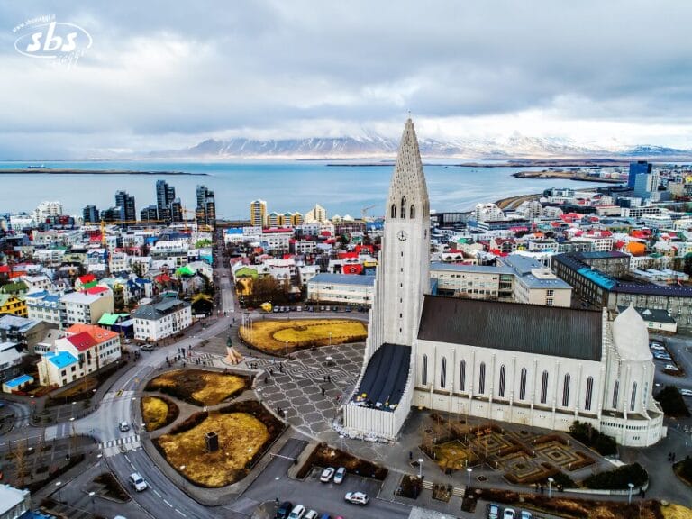 Vista aerea della chiesa di Hallgrímskirkja e degli edifici colorati di Reykjavik, che cattura la vera essenza dell'Islanda con le maestose montagne sullo sfondo.