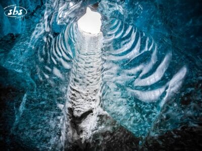 Vista dall'interno di una grotta di ghiaccio blu vicino a Reykjavik, con la luce del sole che illumina le pareti e il soffitto di ghiaccio strutturati e scanalati: uno straordinario esempio delle meraviglie naturali dell'Islanda.