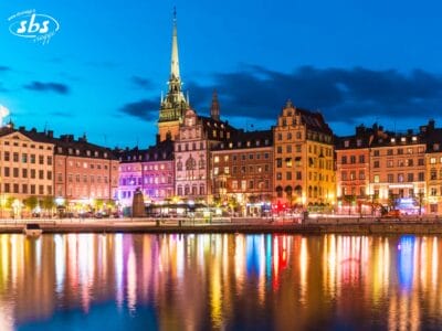 Edifici colorati e guglie di chiese si riflettono sull'acqua al tramonto in un paesaggio urbano di Stoccolma, Svezia.