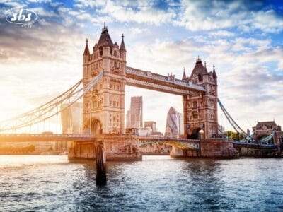 Il Tower Bridge di Londra, in Gran Bretagna, attraversa il Tamigi con due torri e una passerella sopraelevata, sullo sfondo di un cielo parzialmente nuvoloso al tramonto.