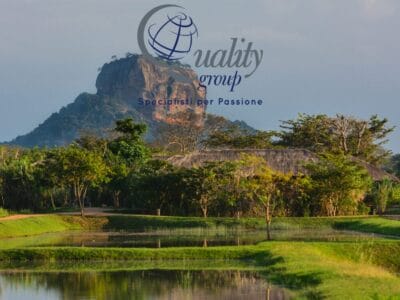 La bellezza della natura è evidente in questo suggestivo paesaggio dello Sri Lanka, dove una vegetazione lussureggiante, una suggestiva formazione rocciosa e un edificio con il tetto di paglia si riflettono nelle acque tranquille: un luogo perfetto per il tuo prossimo tour.