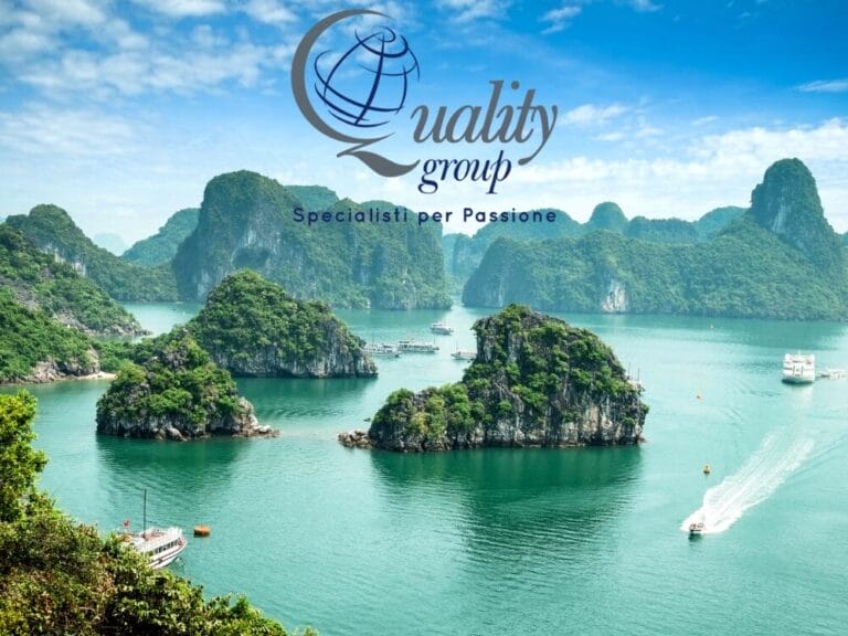Vista panoramica di isole verdi immerse in acque color smeraldo con barche e il logo "Quality Group" sovrapposto in alto: perfetto per un tour classico del Vietnam.