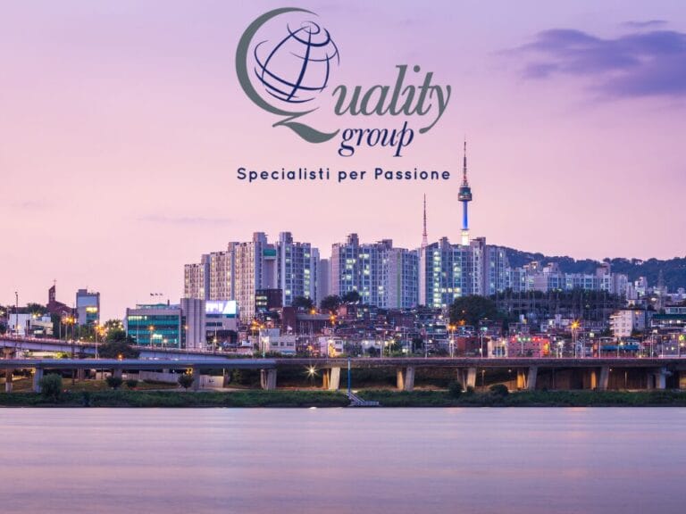 Skyline della città al tramonto in riva a un fiume, con logo "Quality group Specialisti per Passione" e sovrapposizione del testo Gran Tour o Tour Corea.