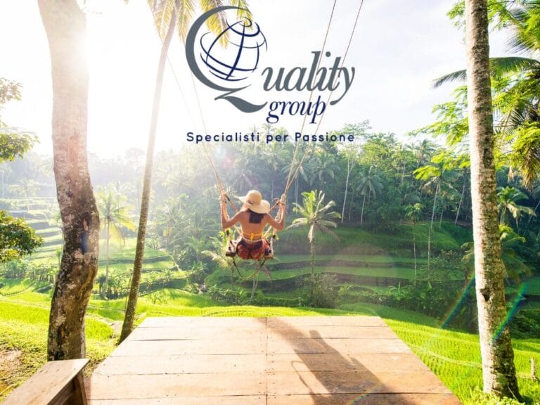 Donna su un'altalena con vista sulle lussureggianti terrazze di riso verdeggianti di Bali, perfetta per il tuo prossimo post su Instagram, con il logo "Quality Group" e il testo in italiano sopra.