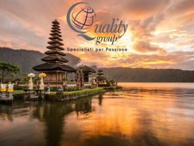 Tempio balinese in riva a un lago al tramonto, che svela i segreti di Bali, con il logo "Quality group" e lo slogan in italiano in alto.