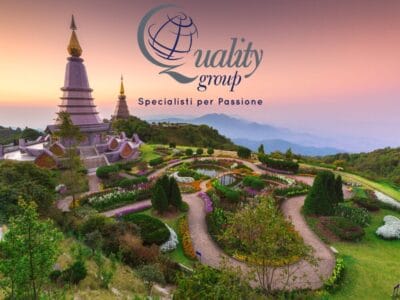 Due pagode in un rigoglioso giardino al tramonto, il logo “Quality group” e la scritta in italiano sovrapposti, evocano il fascino della Thailandia Magica.