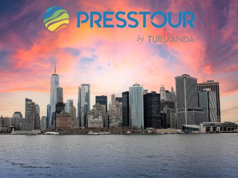 Lo skyline di New York al tramonto con il logo "Presstour by Turisanda" sopra il cielo, che cattura lo spirito vibrante degli Stati Uniti.