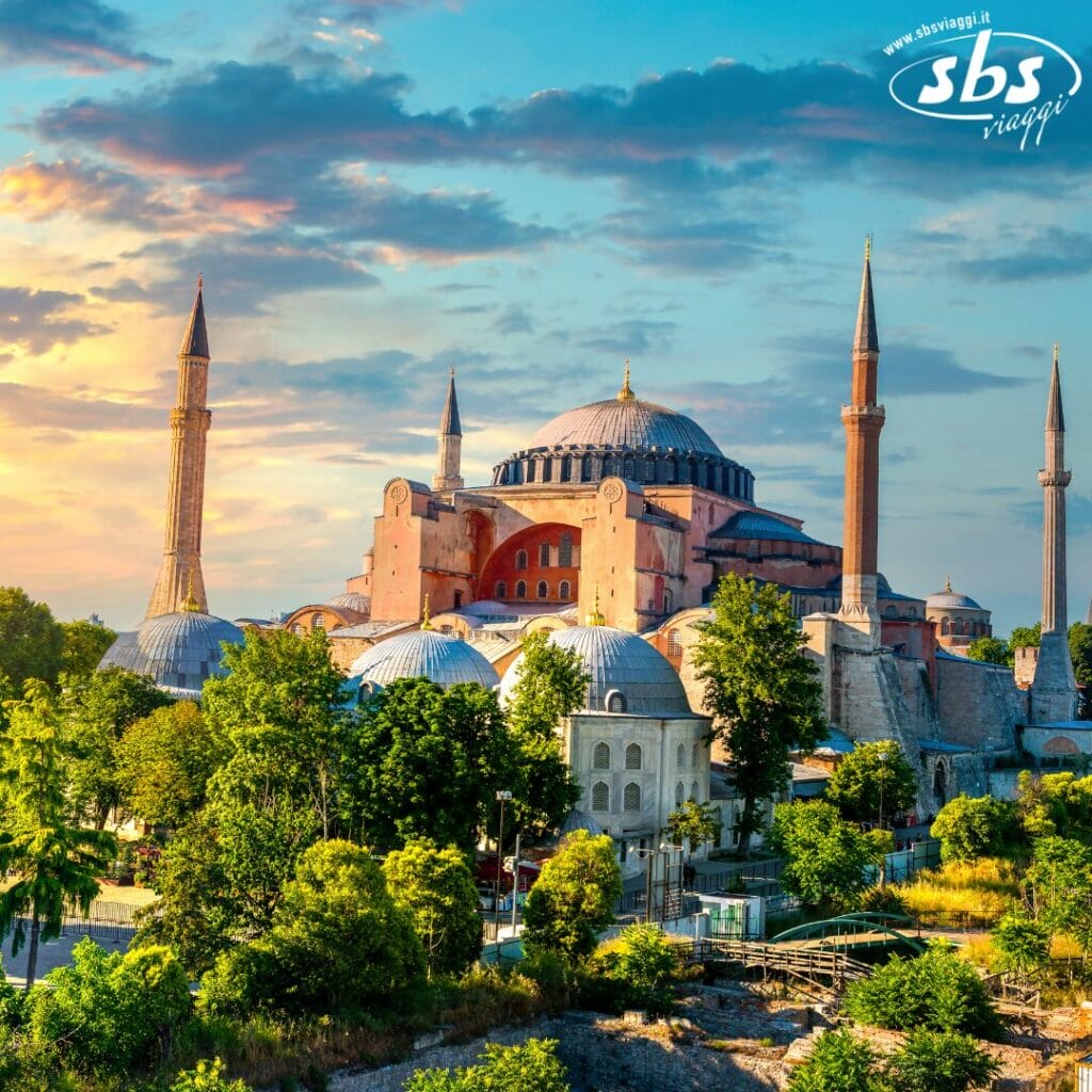 La Basilica di Santa Sofia a Istanbul al tramonto, con i minareti e il verde in primo piano.