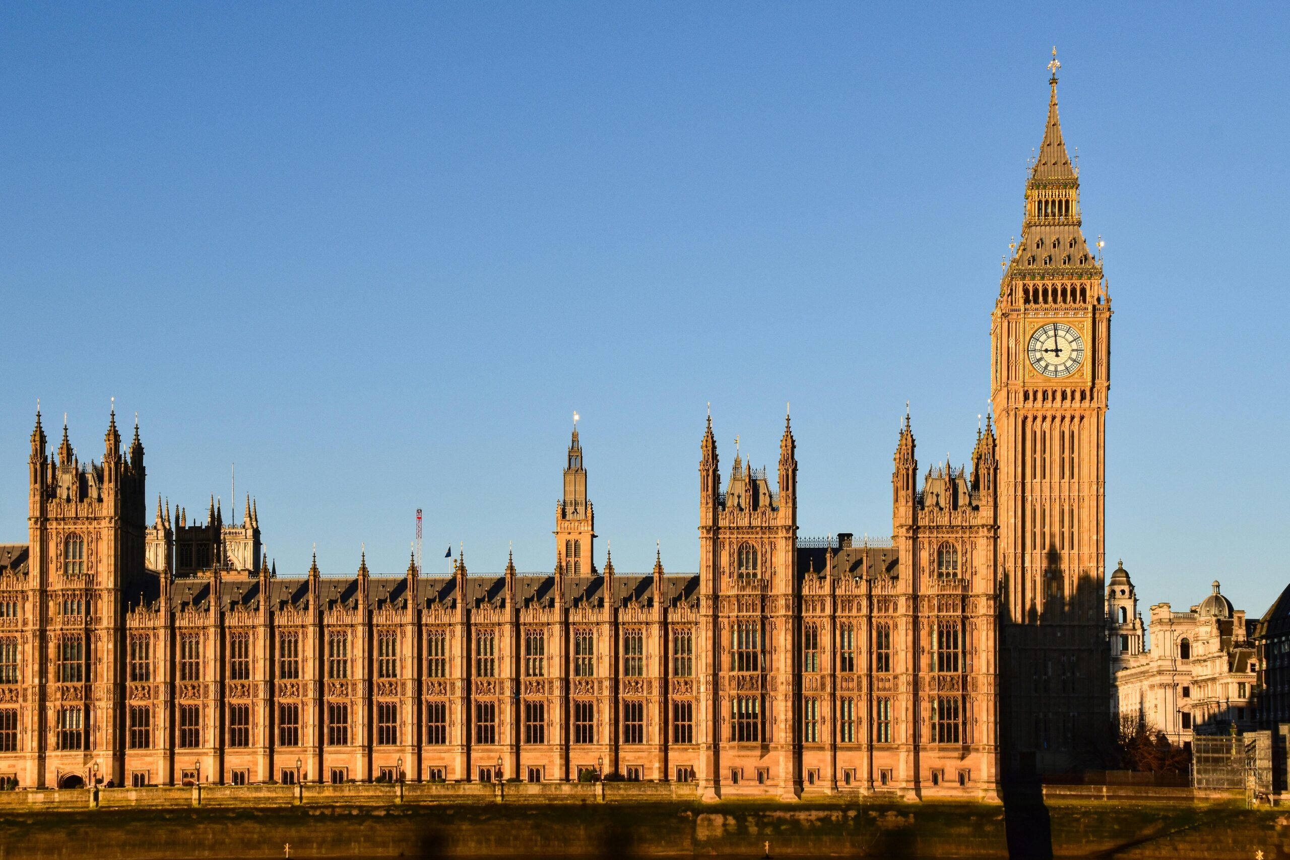 Il Palazzo di Westminster e la torre dell'orologio Big Ben a Londra, immersi nella luce dorata del sole sotto un cielo azzurro e limpido: una vista che ispira chi vuole studiare nel Regno Unito e abbracciare Empowering Students nel suo percorso accademico.