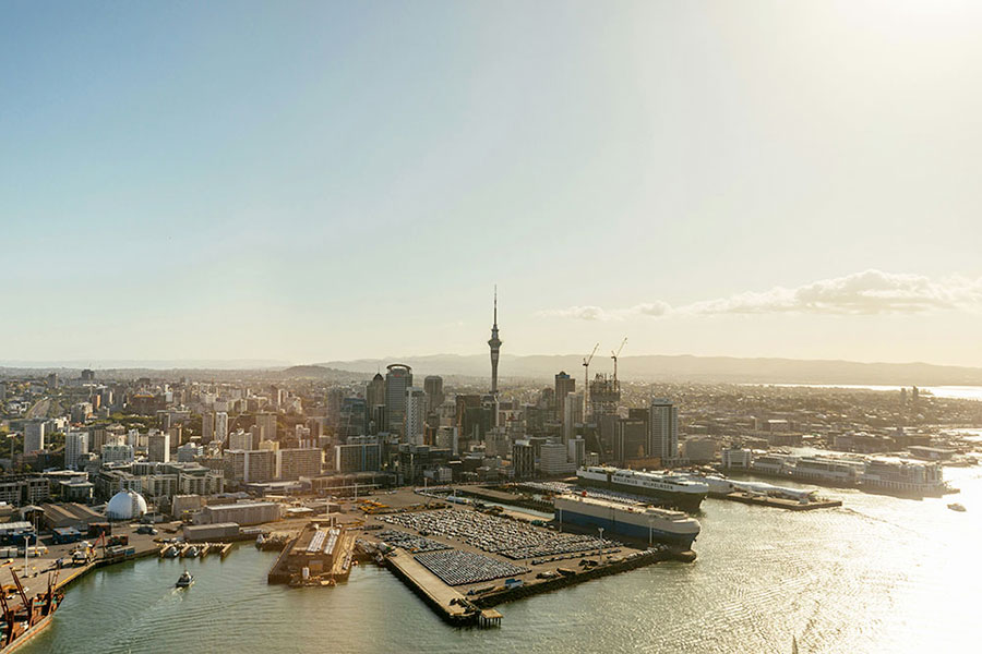 Veduta aerea di una città moderna di Nuova Zelanda con un'alta torre, moli sul lungomare, navi e gru sotto un cielo limpido - perfetta per chi inizia un semestre nuova zelanda o un anno scolastico nuova zelanda.
