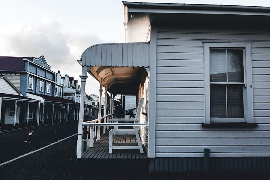 Una tranquilla strada fiancheggiata da antichi edifici in legno evoca il fascino di una città neozelandese, perfetta per chi vuole studiare un anno in Nuova Zelanda, con le sue accoglienti case bianche e le facciate in stile storico che si estendono in lontananza.
